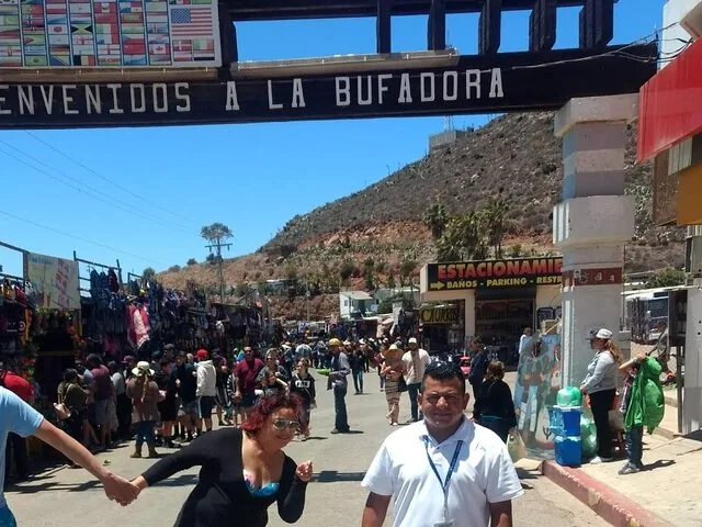 People walking through a lively market area under a welcome sign.